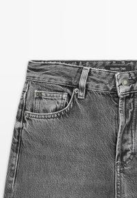 Jeans in denim neri con una cintura anteriore dotata di chiusura a cerniera e bottone, cinque tasche e un effetto sbiadito. Etichetta del marchio visibile.