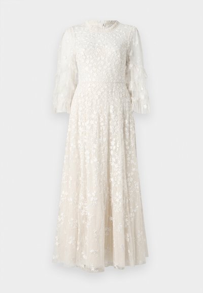 Robe longue en crème clair, brodée de fleurs, avec des manches en tulle volantées et un corsage ajusté, se déployant en une jupe évasée.