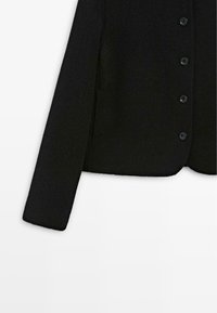 Black wool blend jacket with a soft texture, featuring a round neckline, long sleeves, and six black buttons down the front.