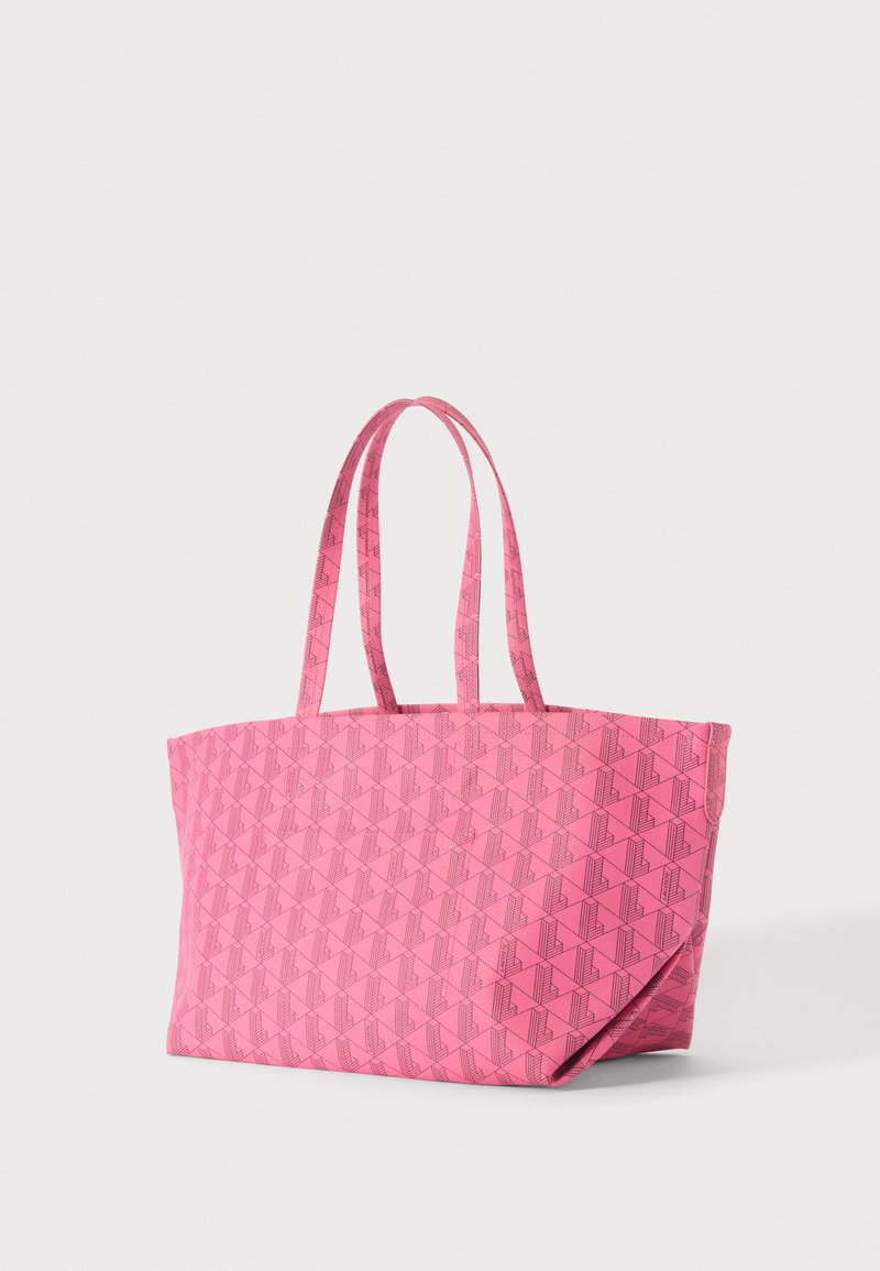 Pink tote bag with a geometric pattern and two long handles, shown on a plain light background.