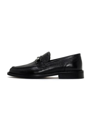 Mocasines de cuero negro con un acabado texturizado, diseño sofisticado, suela plana y detalle en metal plateado en la parte delantera.
