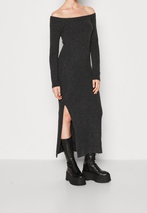 Schulterfreies, langärmliges, dunkelgraues Strickkleid mit einem Seiten-Schlitz, kombiniert mit schwarzen Schnürplattformstiefeln. Glatte Textur.