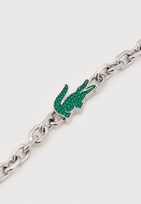 Ασημένιο βραχιόλι αλυσίδας με γοργόνα διακοσμημένη με πράσινες στρας, σε απλό λευκό φόντο.