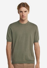 Kortärmad, olivgrön stickad tröja gjord av ett mjukt, texturerat material, med rund halsringning och ribbade ärmslut.