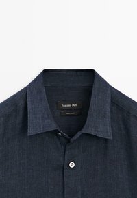 Dark blue button-up shirt with pointed collar, single visible button fastened, and Massimo Dutti brand label inside collar.