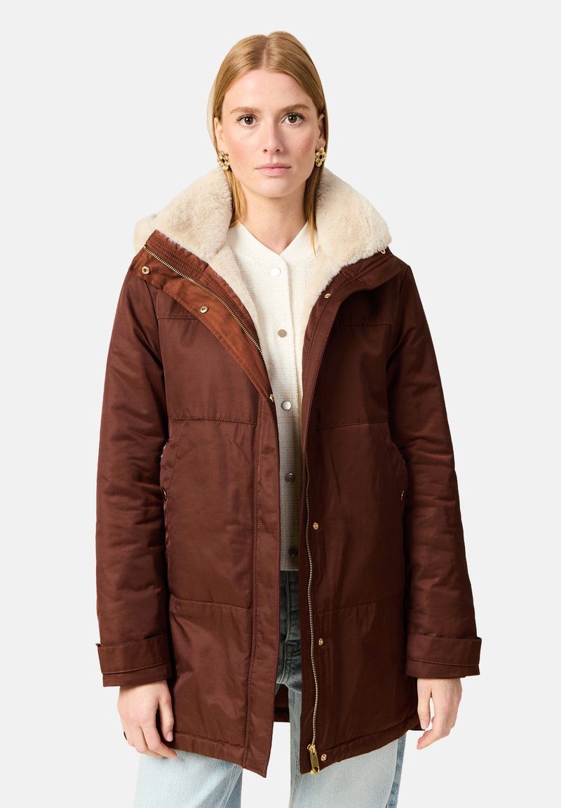 Ruskea eristävä takki, jossa on tekoturkiskaulus, vetoketju ja nepparit, kaksi etutaskua ja ribbikuvioidut hihansuut.