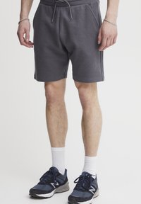 Gray textured shorts with an elastic waistband and drawstring, featuring side pockets. Worn with white crew socks and navy athletic shoes.