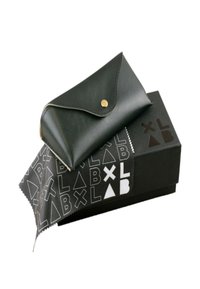 Custodia in pelle nera con un bottone a pressione dorato, appoggiata su una scatola nera con un motivo geometrico bianco. Include un panno per la pulizia.