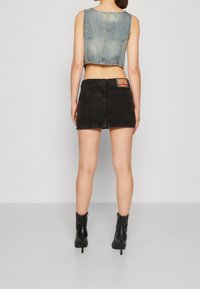 Besluttet blå denim top og sort denim mini nederdel. Sættet har et synligt mærke på taljen og sorte ankelstøvler.