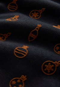 Tessuto scuro con motivo di ornamenti natalizi arancioni e fiocchi di neve. Superficie strutturata con aspetto morbido e intrecciato.