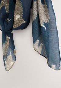 Sciarpa blu scuro con una tessitura strutturata, caratterizzata da un motivo di animali color chiaro con corna. I bordi sono rifiniti e leggermente sfrangiati.