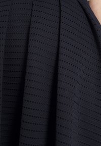 Mörk marinblå texturerad tyg med horisontella ränder och små hål. Mjukt material med en liten glans och följsam draping.