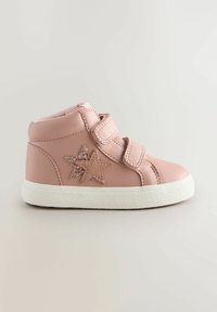 Bottines en simili cuir rose avec deux appliqués en étoile pailletés, semelle en caoutchouc blanche et deux bandes Velcro pour la fermeture.