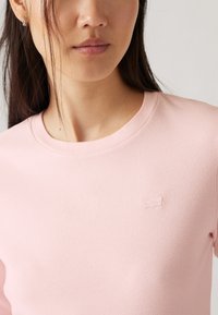 Lichtroze katoenen sweatshirt met een ronde halslijn en een gestructureerde afwerking, voorzien van een klein geborduurd logo op de borst.