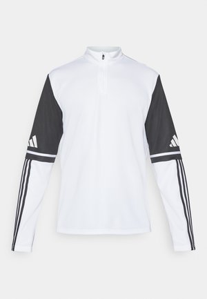 Camiseta de manga larga deportiva con un cuerpo blanco y mangas negras, con un cuello de cremallera de cuarto, logo de Adidas y franjas en contraste en los brazos.