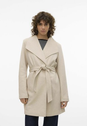 Manteau beige ceinturé avec un col châle, des manches longues et une texture douce, superposé sur un haut rayé noir et blanc.