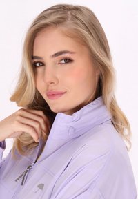 Jasnofioletowa kurtka z wysokim kołnierzem, zapinana na zamek, z subtelnym logo parasola. Gładka faktura i swobodny krój, idealna na zewnątrz.