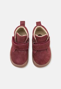 Bordowe zamszowe botki za kostkę z rzepem, beżowym wykończeniem wewnętrznym i gumową podeszwą. Płaskie, zaokrąglone noski z wzmocnionym przeszyciem.