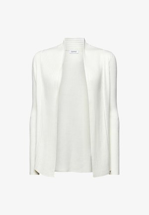 Mujer con una camiseta roja, cárdigan blanco de canalé y falda gris plisada con pequeño patrón geométrico, sosteniendo los bordes del cárdigan abiertos.