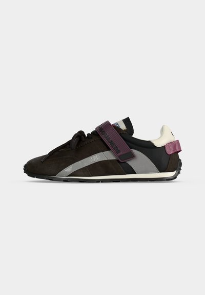 Baskets noires et grises profil bas avec bande violette, languette de talon blanche et semelle texturée.