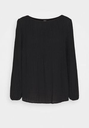 Blouse noire à manches longues avec encolure ronde et de subtils plis verticaux sur les manches et le haut du corps.