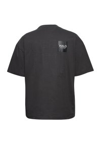 T-shirt noir oversize avec texte embossé "OFF DUTY GEAR" et un petit patch noir brillant indiquant "HALO 1986/072981" sur le haut du dos.