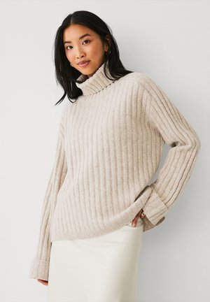 Light beige ribbed turtleneck sweater with a relaxed fit and dropped shoulders. Soft texture, long sleeves, and a slightly oversized silhouette.