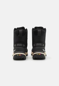 Black high-top boots featuring a textured fabric upper, reinforced heel, and a colorful striped accent on the sole. Rubber outsole for traction.