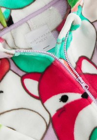 Pyjama en polaire à fermeture éclair avec un motif animal coloré, principalement rouge et vert. Texture douce avec une fermeture éclair lavande et une doublure intérieure.