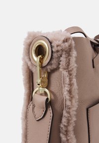 Borsa in pelle beige con un morbido bordo testurizzato rosa, accessori in oro e un distintivo dettaglio con chiusura a molla sul lato.