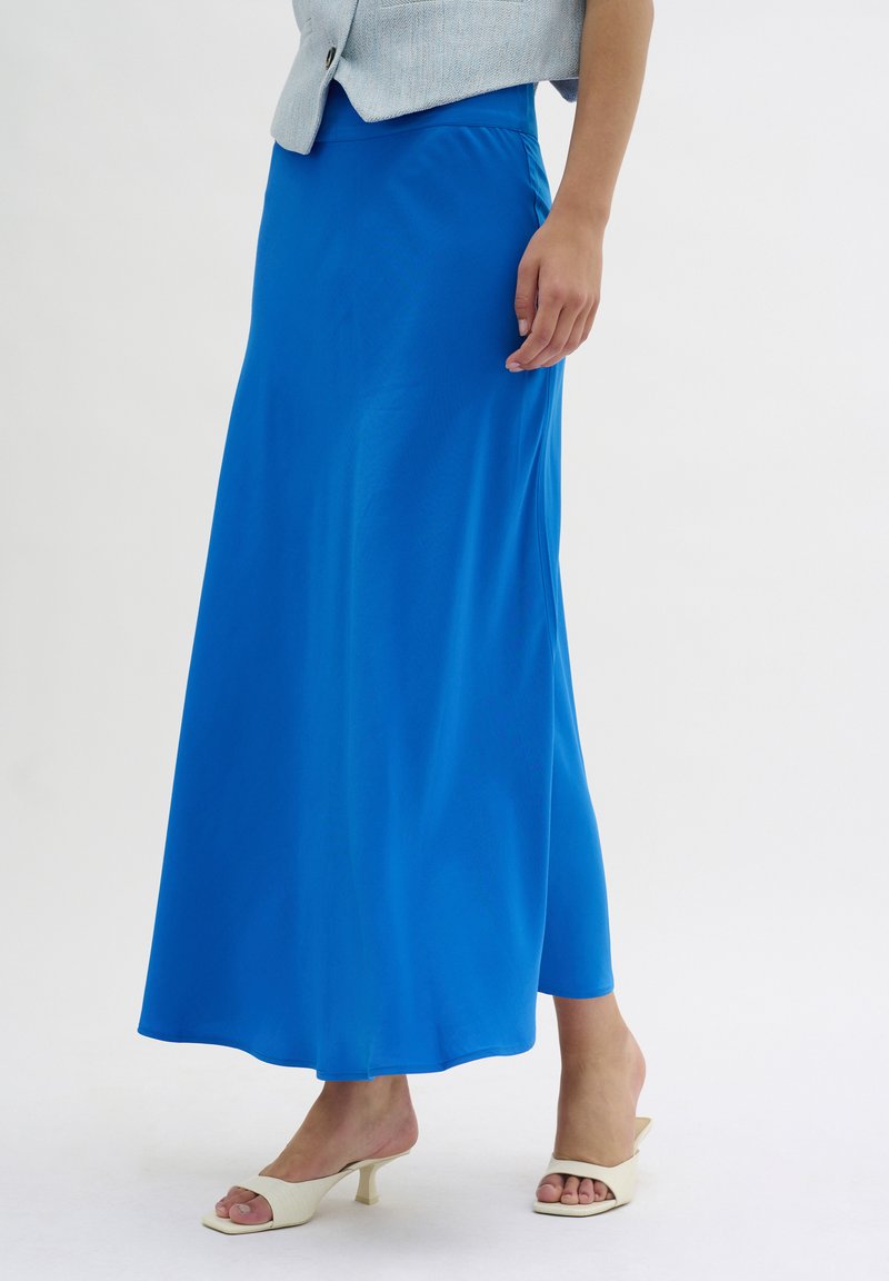 Blaue Maxiröhre aus einem glatten, leichten Stoff mit fließender Silhouette. Getragen mit cremefarbenen Riemchensandalen; minimalistisches Design.