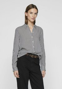 Black and white striped button-up shirt with a collar, long sleeves, and a loose fit, paired with black pants and a brown belt.