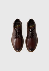 Zapatos de cuero marrón con un acabado suave, puntera redonda, diseño de cordones y costuras en contraste. El interior presenta una etiqueta de marca y comodidad amplia.