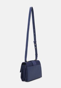 Borsa a tracolla blu navy con finitura texturizzata. Presenta una patta in suede, una tracolla regolabile e dettagli in metallo dorato. Forma rettangolare compatta.