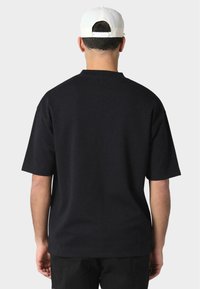 Black, short-sleeved t-shirt with a relaxed fit, made of cotton. Seen from the back, features a simple design and smooth texture.