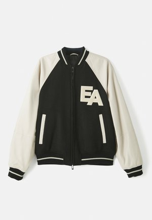 Black and white varsity jacket with cream sleeves, front zipper, striped cuffs, and "EA" letters on the left chest.