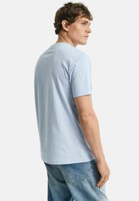 Lichtblauw T-shirt met korte mouwen van zacht katoen, met een normale pasvorm en een ronde hals, gecombineerd met lichtblauwe denim jeans.