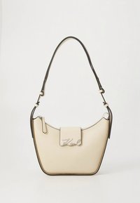 Creamfarvet læderhåndtaske med sort kant, buet form, topklaplukning og sølv logo-accent. Justerbar skulderrem.