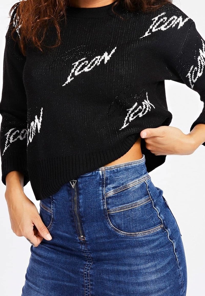 Černý pletený svetr s bílým nápisem "Icon", zkrácený lem a žebrované manžety, v kombinaci s modrou mini sukní z denimu s vysokým pasem a zipem.