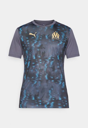Moška Puma majica v mornarsko modri barvi s teksturiranim vzorcem, ki ima modre detajle. Zlata Marseillejeva značka in besedilo "Droit au But", kratki rokavi.
