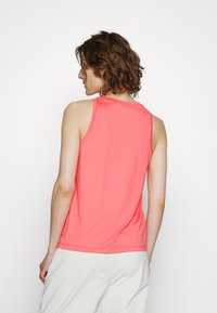 Top de tanque coral feito de tecido suave, com um corte relaxado e alças largas. Textura lisa com detalhes de costura mínimos.