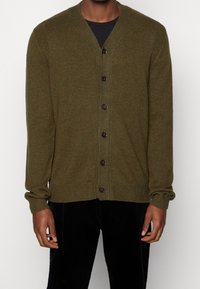 Olivgrön kofta i mjukt stickat material, med V-ringning, långa ärmar och sex bruna knappar framtill.