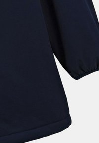 Mörkblå plagg med en slät yta, som har långa, sammandragna ärmar och en rundad nederkant. Enkelt design, inga synliga mönster eller hårdvara.