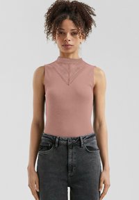 Mauve brezrokaven bodysuit z visokim ovratnikom, okrašen z čipkastim robom in teksturiranim vzorcem, v kombinaciji s temno modrimi kavbojkami z visokim pasom.