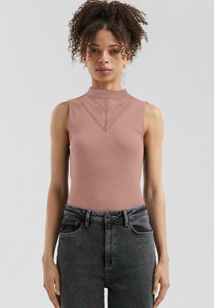Un body sans manches mauve avec un col montant, orné d'une bordure en dentelle et d'un motif texturé, associé à un jean taille haute en denim foncé.