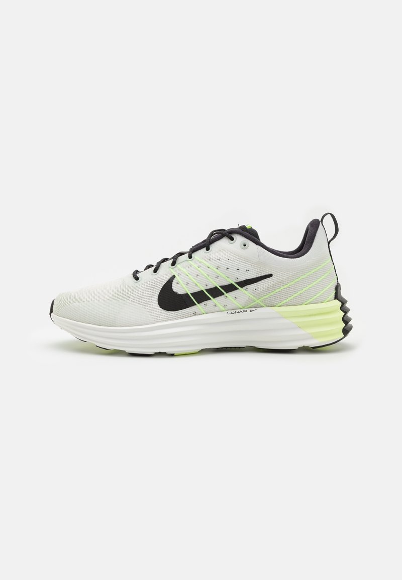 Běžecké boty Nike s síťovaným svrškem v bílé a černé barvě, s neonově zelenými akcenty, kulatou špičkou a polstrovanou mezipodešví.