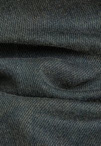 Tela de mezclilla oscura con una textura suave, que presenta un sutil patrón de sarga y suaves pliegues. El color es azul intenso con un ligero brillo.