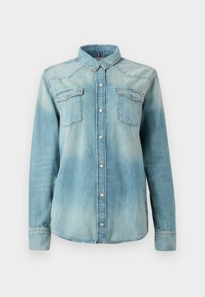 Ljust blå denimskjorta med lång ärm, spetskrage, två bröstfickor och knappstängning fram. Har urtvättad och texturerad tyg.
