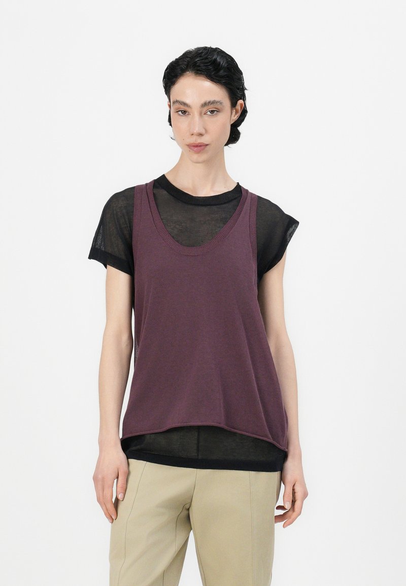 Paarse tanktop bovenop een doorzichtige zwarte t-shirt, met een ronde halslijn en een ontspannen pasvorm, gecombineerd met beige broeken.