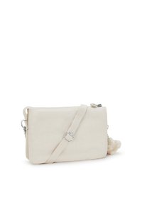 Borsa a tracolla beige realizzata in morbido tessuto, con chiusura a zip, tracolla regolabile e un dettagli pom-pom soffice sul lato.